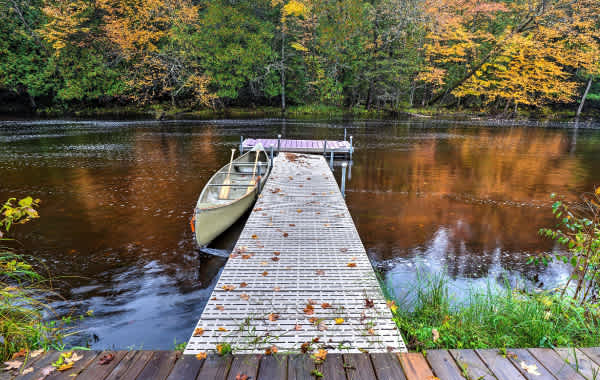 Fall scene of lake with a wooden dock leading out to a canoe