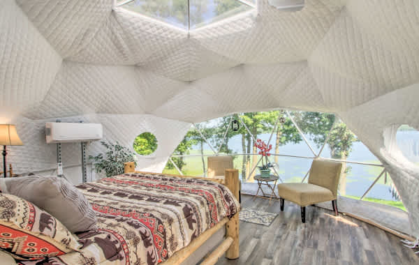 Interior shot from inside a yurt, looking out the window to a lakeside view in a vacation rental