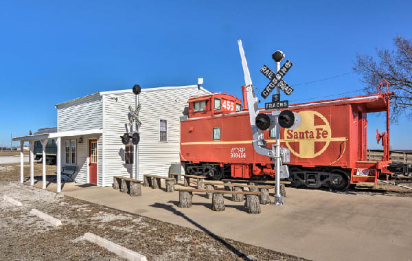 Unique vacation rental home built in an old train car and caboose with outdoor benches and a vintage railroad crossing sign.