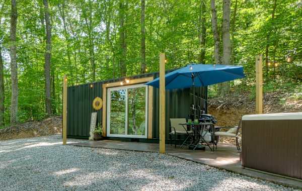 A shipping container tiny home in Loudonville, Ohio with a "welcome" sign and strung lights