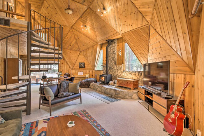 Cozy living room with wood-burning stove and guitar at the unique Dome House vacation rental in Idyllwild, California