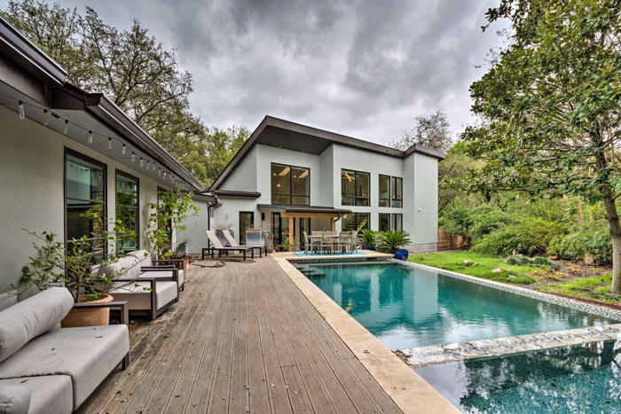 Lush background with in-ground pool at modern vacation rental in Austin, Texas