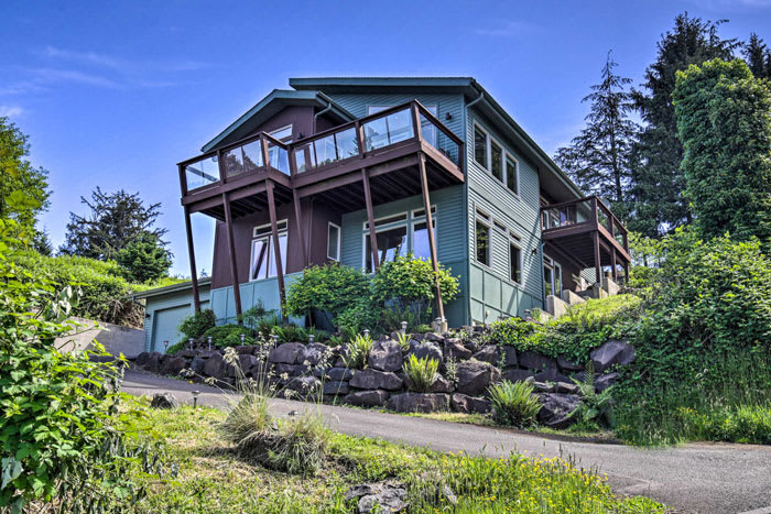 Exterior view of Bay City, Oregon hilltop vacation rental with stilted decks and lush landscaping