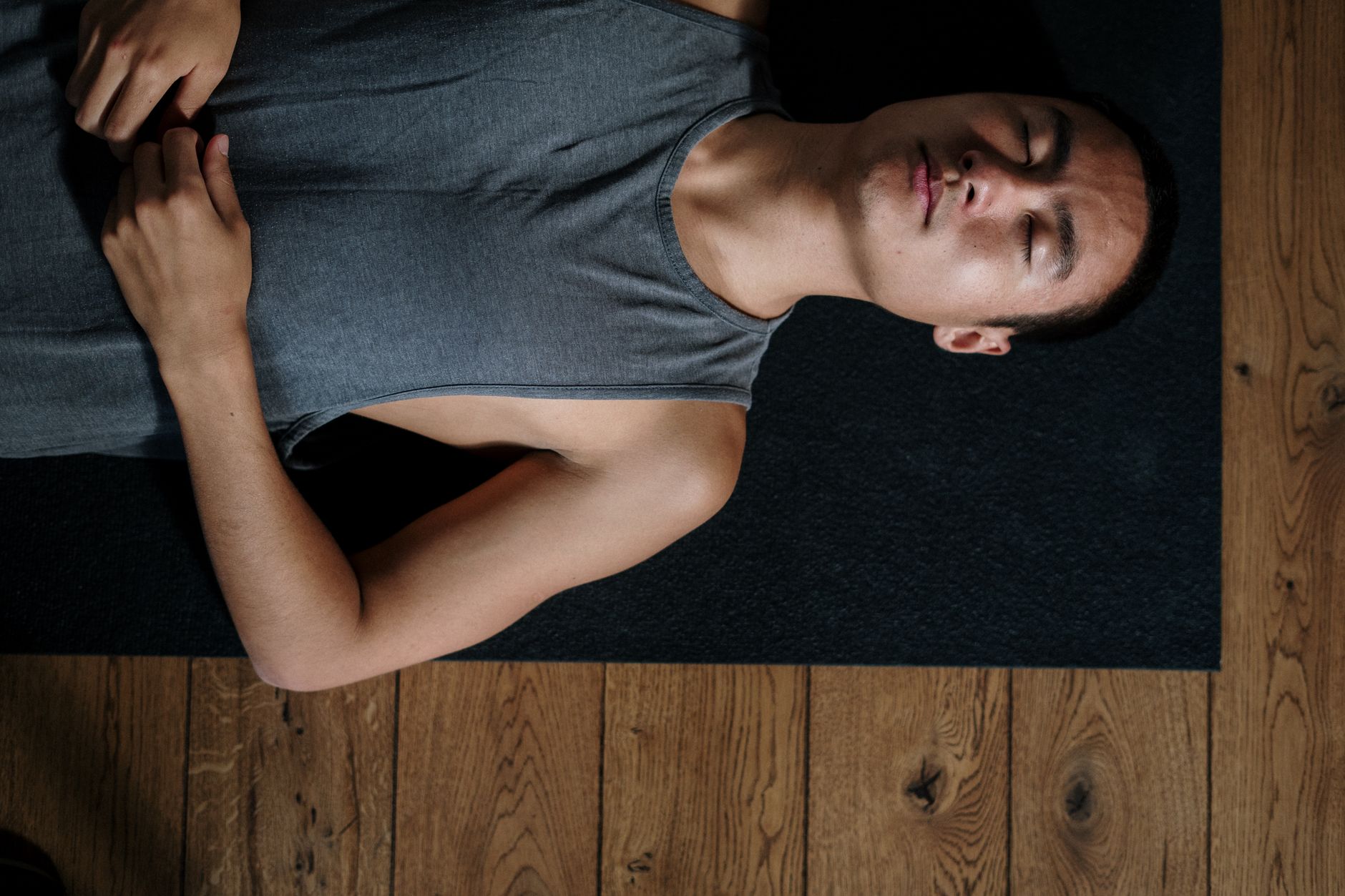 Man in Gray Tank Top Lying on Black Carpet