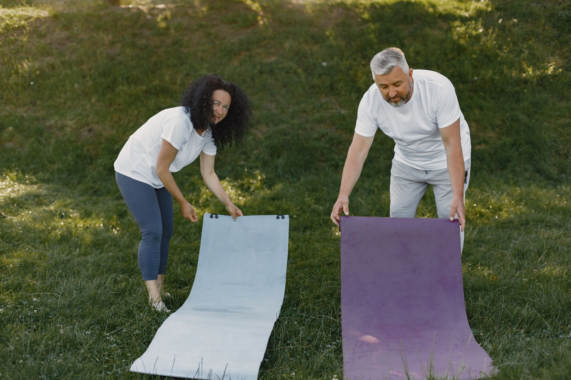A Couple Rolling Out Yoga Mats on the Grass