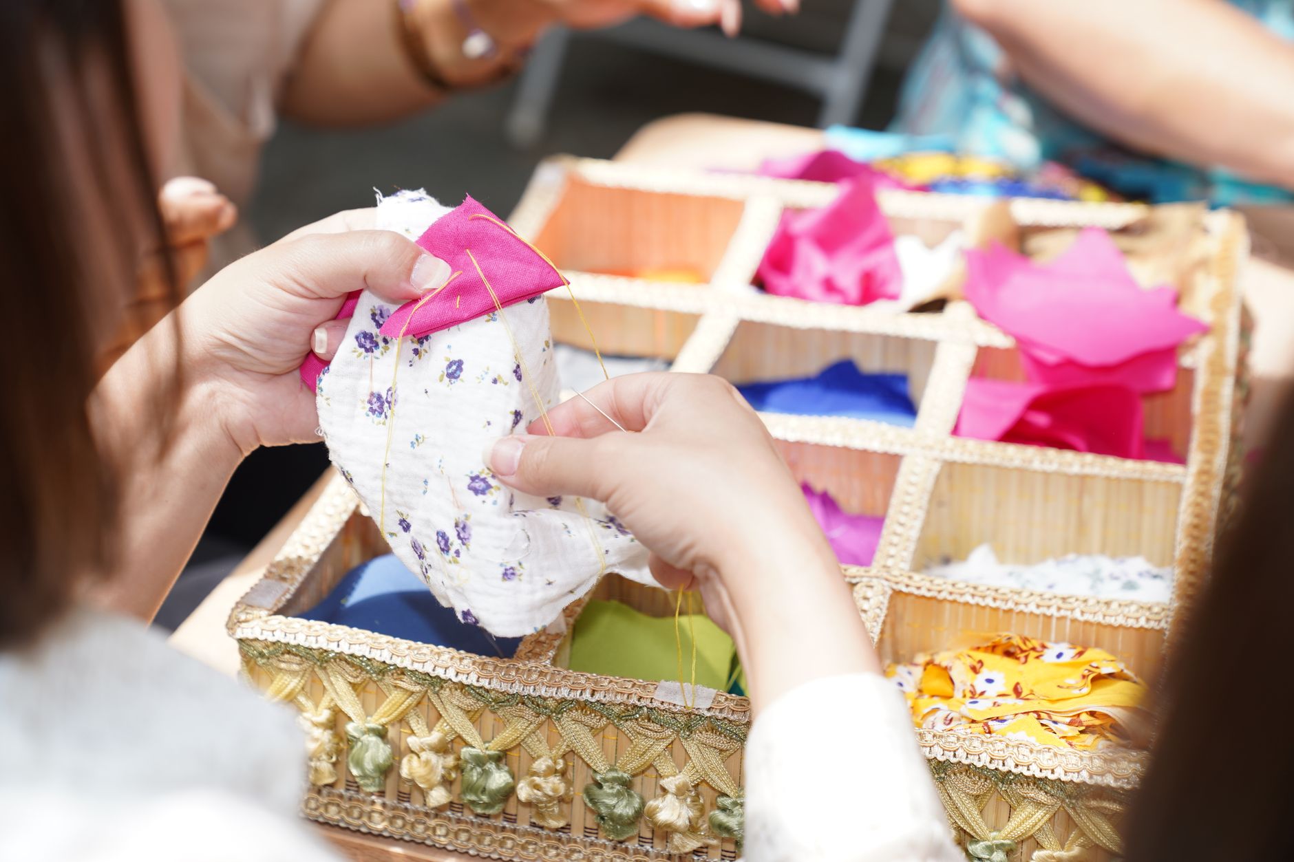 Hands Sewing with Colorful Fabric Swatches