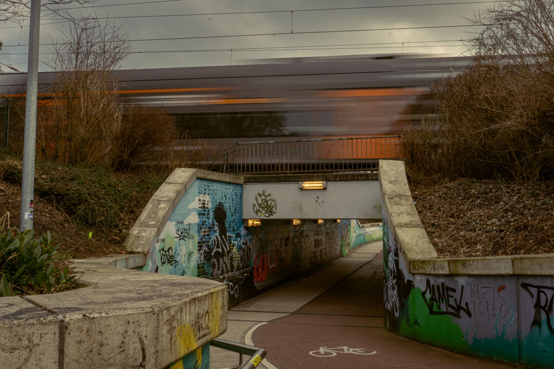 Vibrant Graffiti Underpass with Passing Train in Kamen