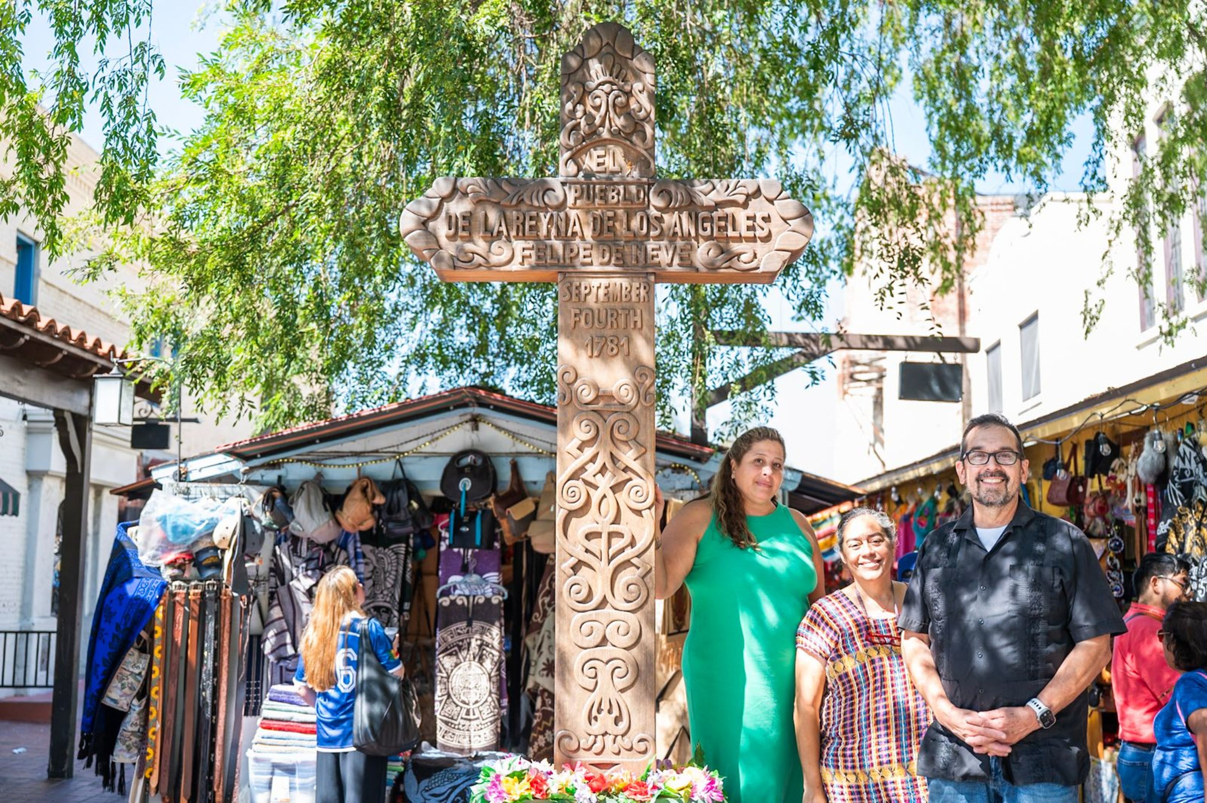 Los Angeles merchants Sylvia Gribbell, Valerie Hanley, and Eddie Flores stand next to the Olvera Street cross in Los Angeles. | Credit: Becket