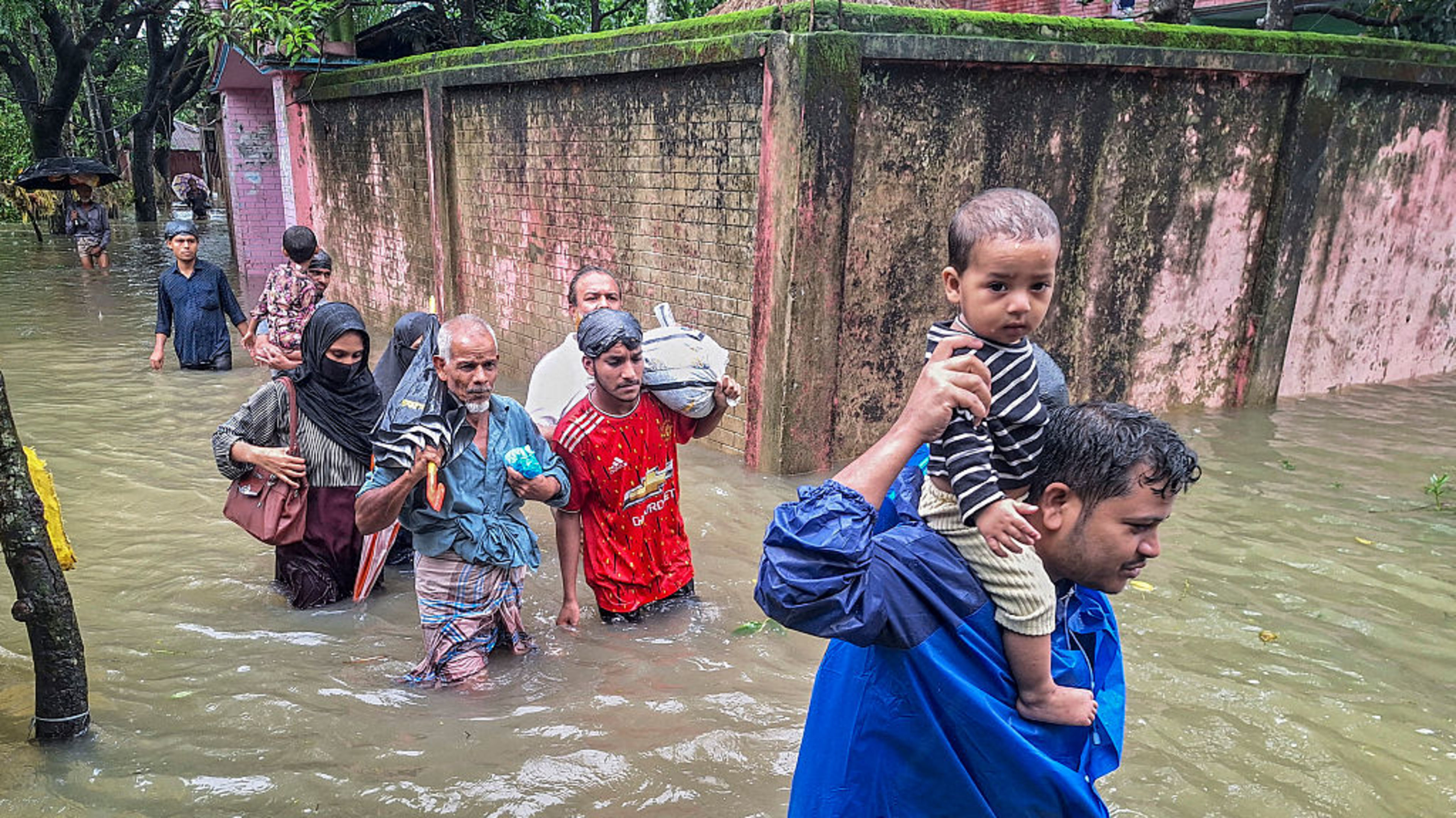 Residents wade through floodwaters after heavy monsoon rains in Chattogram, Bangladesh, on July 12, 2026. Flash floods and landslides triggered by monsoon rains have killed dozens of people in Bangladesh in the past week, officials said on July 12, with tens of thousands displaced from their homes. | Credit: Rabin Chowdhury/AFP via Getty Images