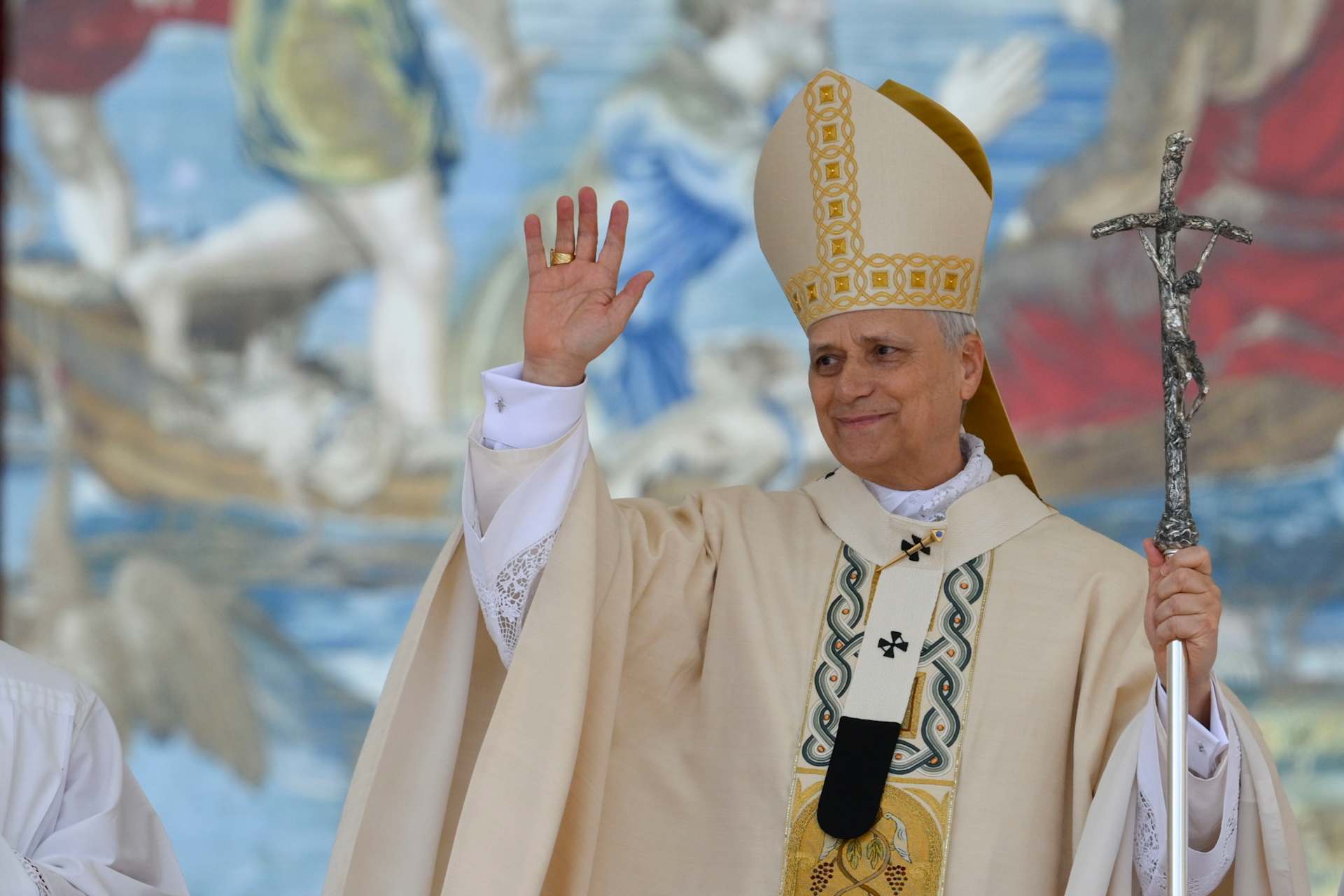 Pope Leo XIV waves during the inaugural Mass of his pontificate, held in St. Peter's Square on May 18, 2025. He stands in front of a Flemish tapestry depicting the dialogue between Jesus and Peter after the miraculous catch of fish. - Credit: Vatican Media