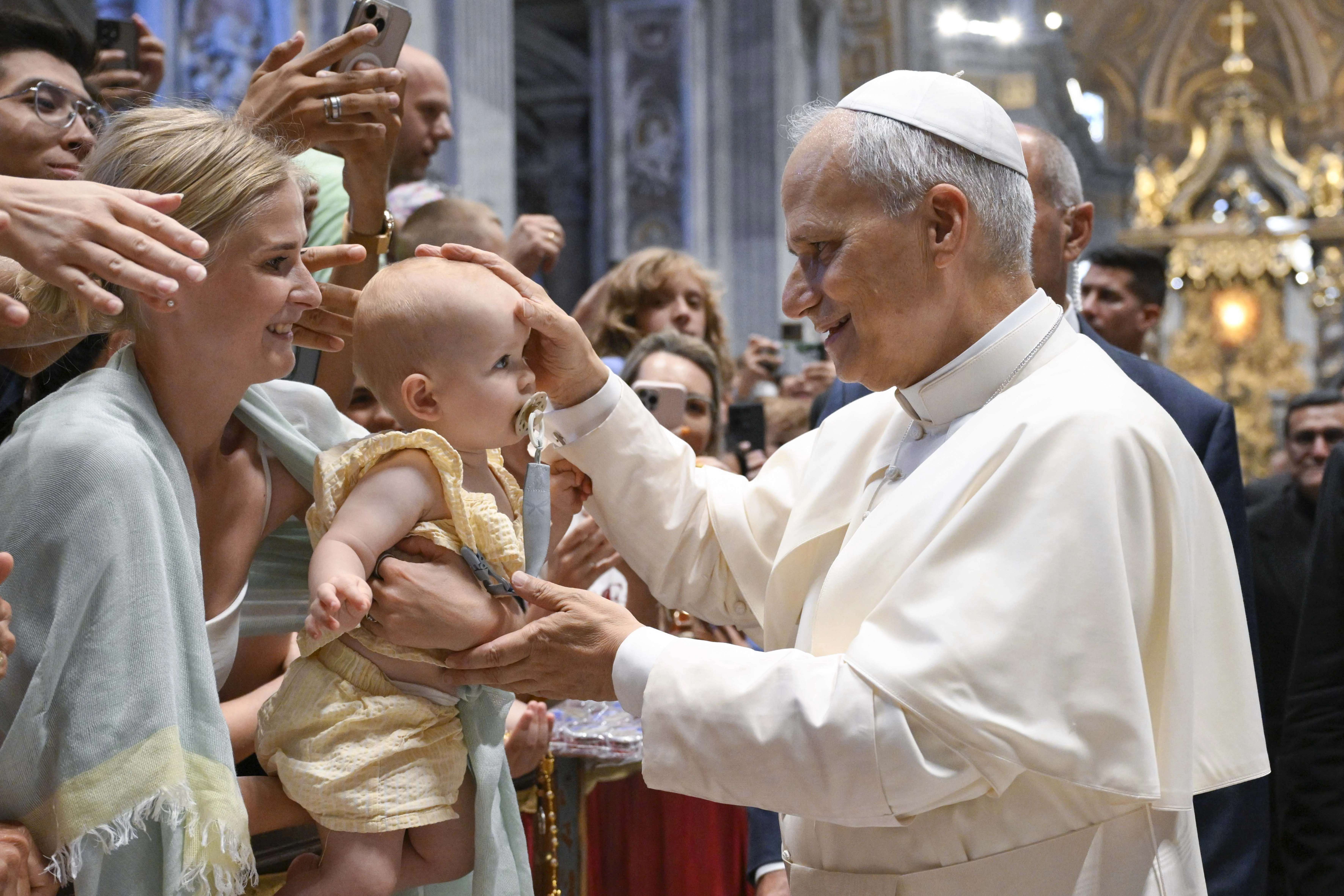 Pope Leo XIV blesses a baby during his Wednesday general audience in St. Peter’s Basilica on Aug. 13, 2025, at the Vatican. Due to the heat, the pope gave his address in Paul VI Audience Hall but also greeted pilgrims in other locations. Credit: Vatican Media