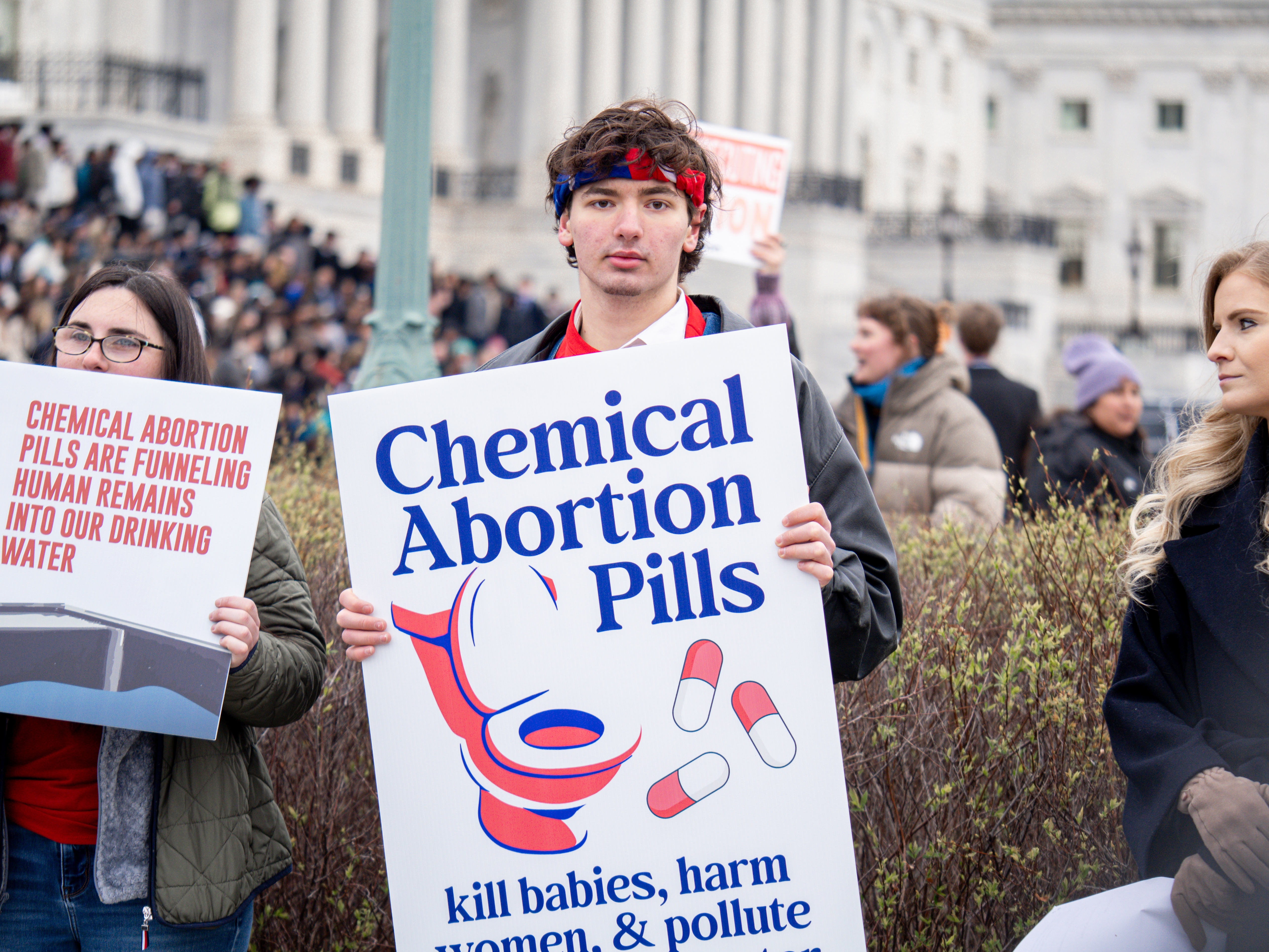 A supporter of the Clean Water for All Life Act holds a sign about the environmental impact of chemical abortion pills on March 18, 2026. | Credit: Students for Life