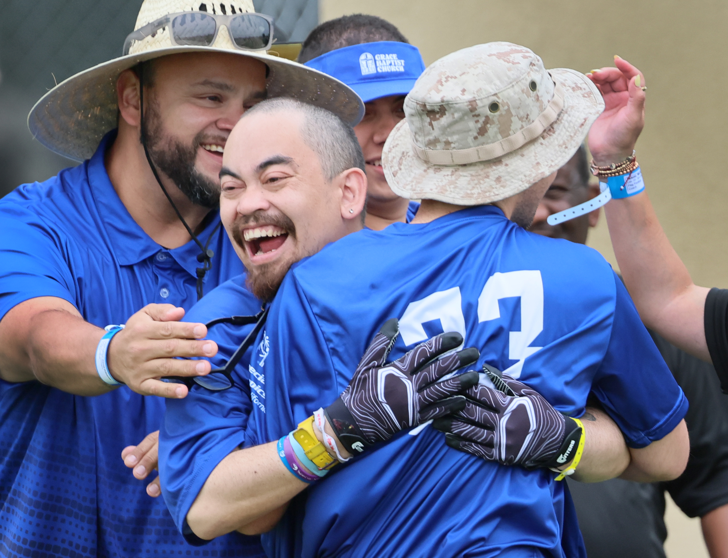 Special Olympics athletes celebrating together on football field wearing team uniforms and medals