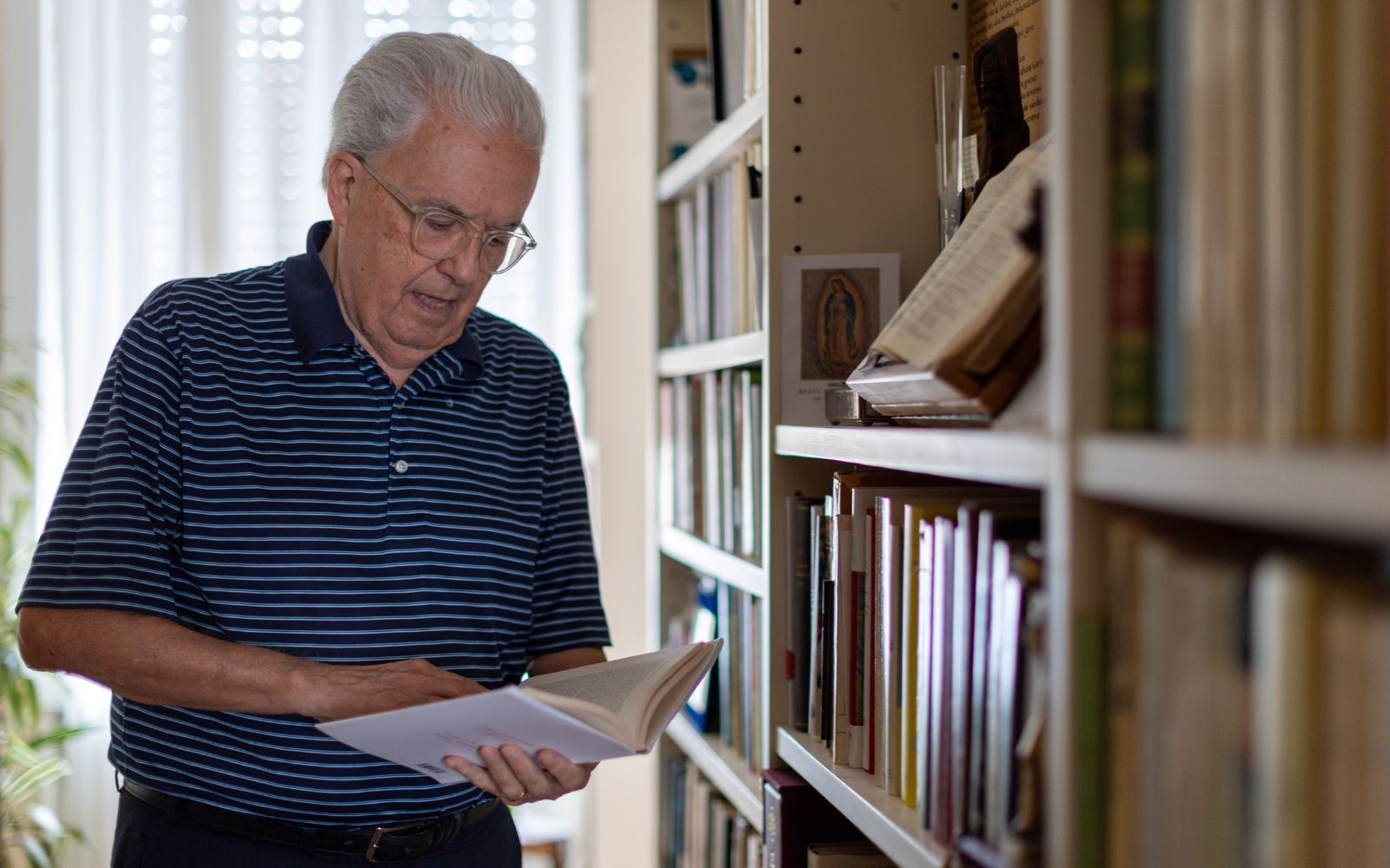 Carriquiry ojea un libro en su casa | Crédito: Daniel Ibañez/ EWTN News