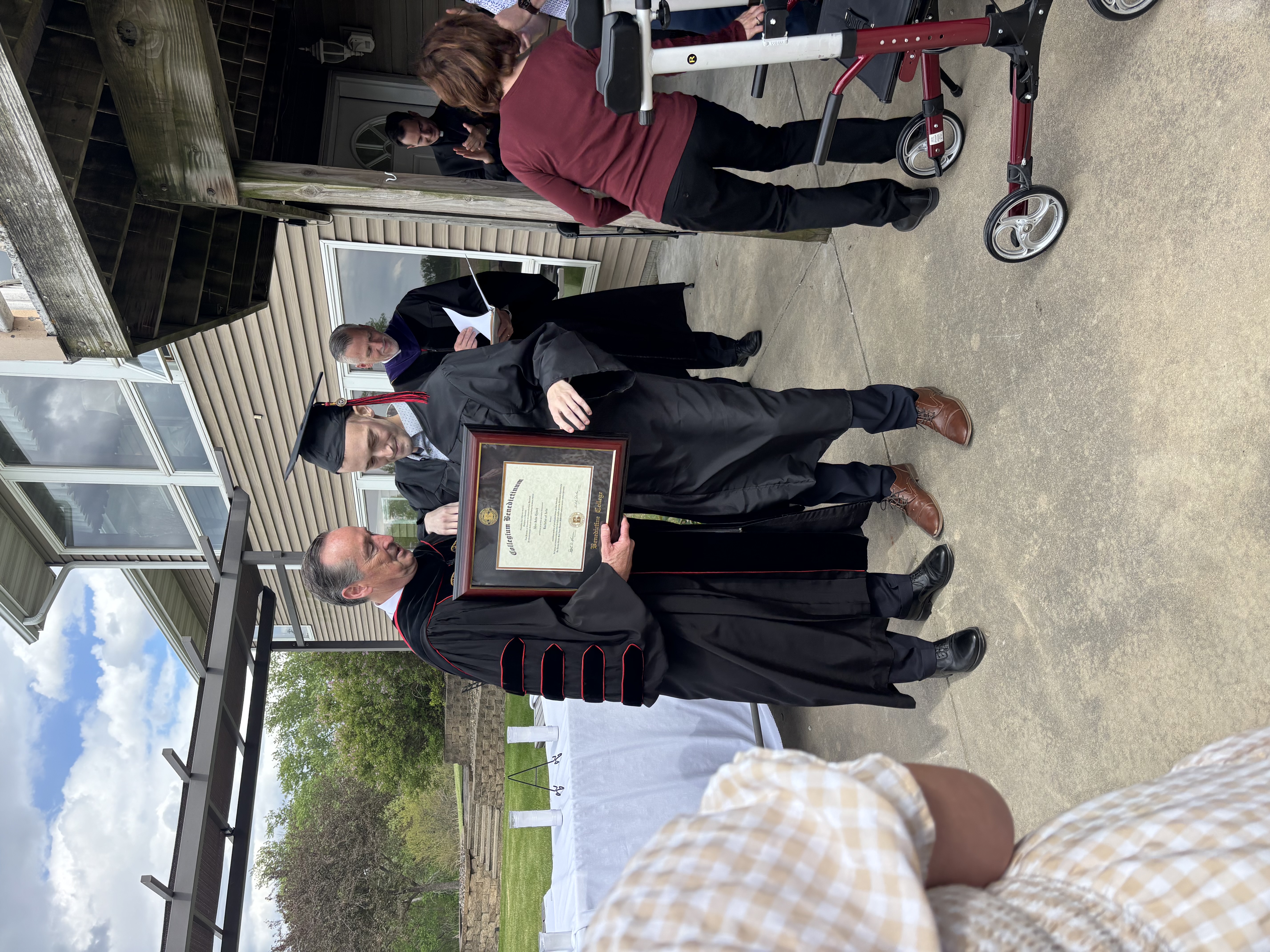 Alex Lynch and Benedictine College President Stephen Minnis with diploma at Lynch’s at-home commencement ceremony on May 7, 2026. | Credit: Photo courtesy of Finnegan Ritchie