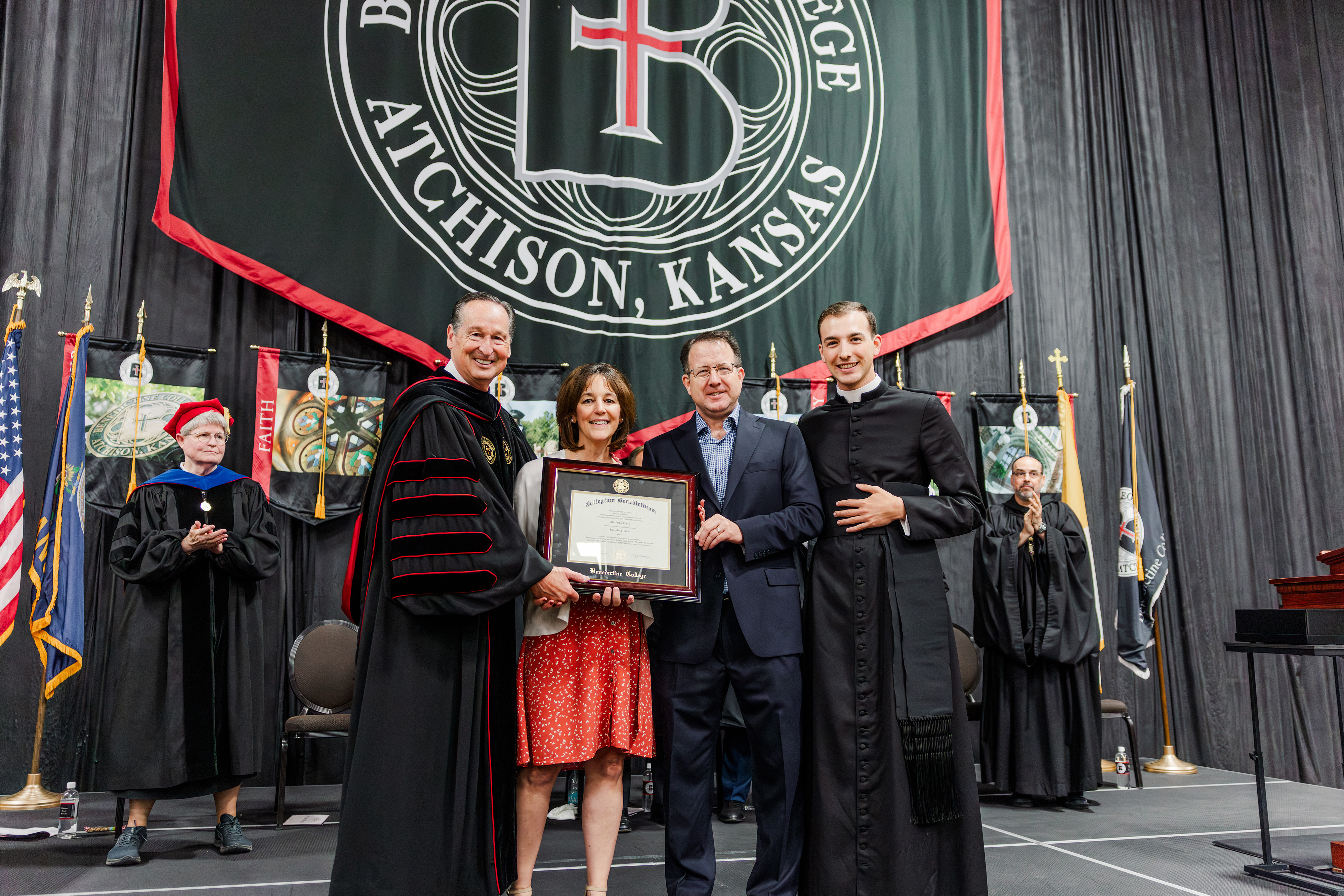 Alex Lynchʼs parents and brother accept Lynch’s framed diploma at graduation on May 16, 2026. | Credit: Isabella Wilcox/Benedictine College