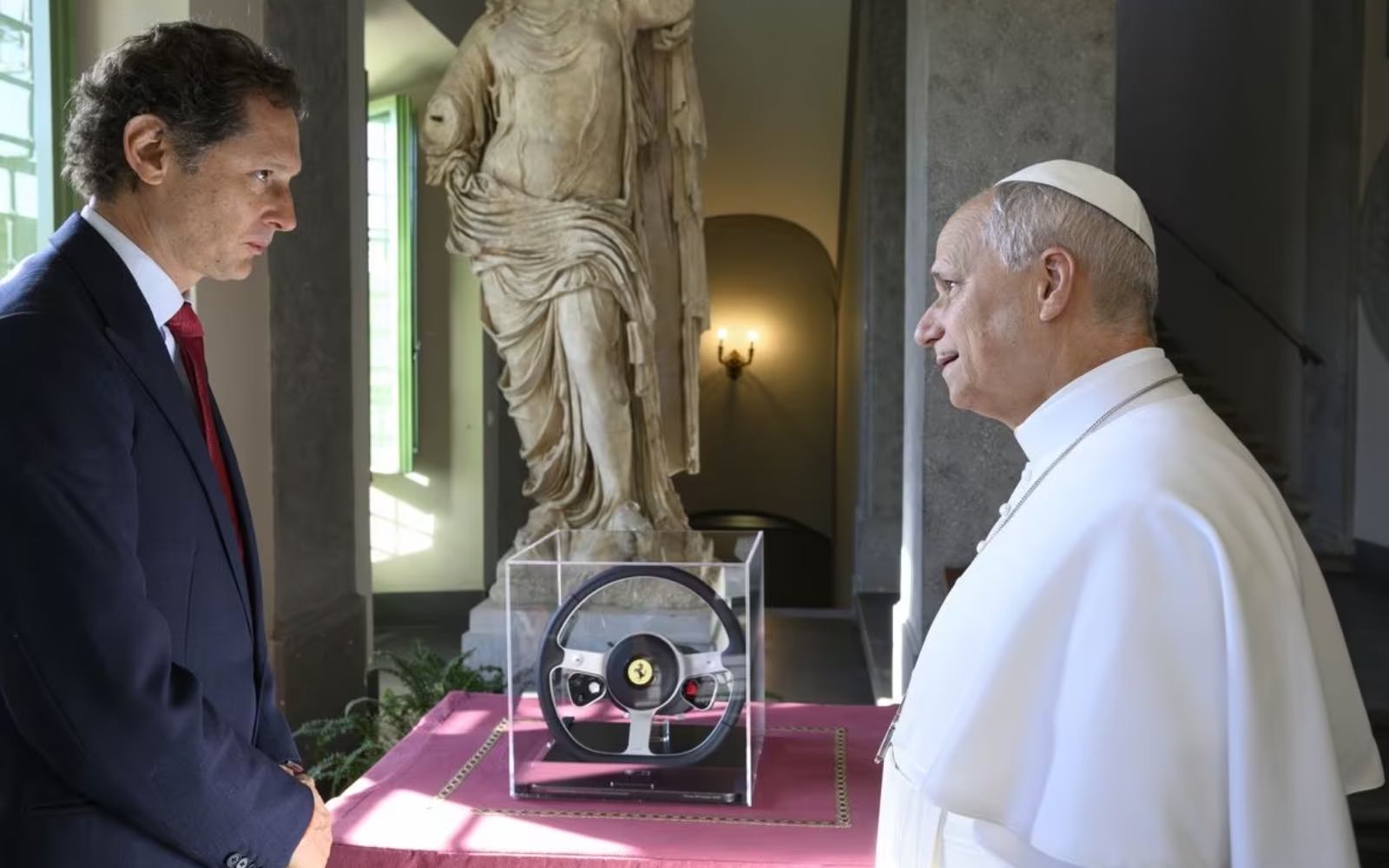 Pope Leo XIV receives from Ferrari chairman John Elkann the steering wheel of a Ferrari Luce, the Italian luxury sports car manufacturer’s first fully electric car, which the pope got to see during a meeting with a delegation from Ferrari at Castel Gandolfo, south of Rome, on May 26, 2026. | Credit: Ferrari