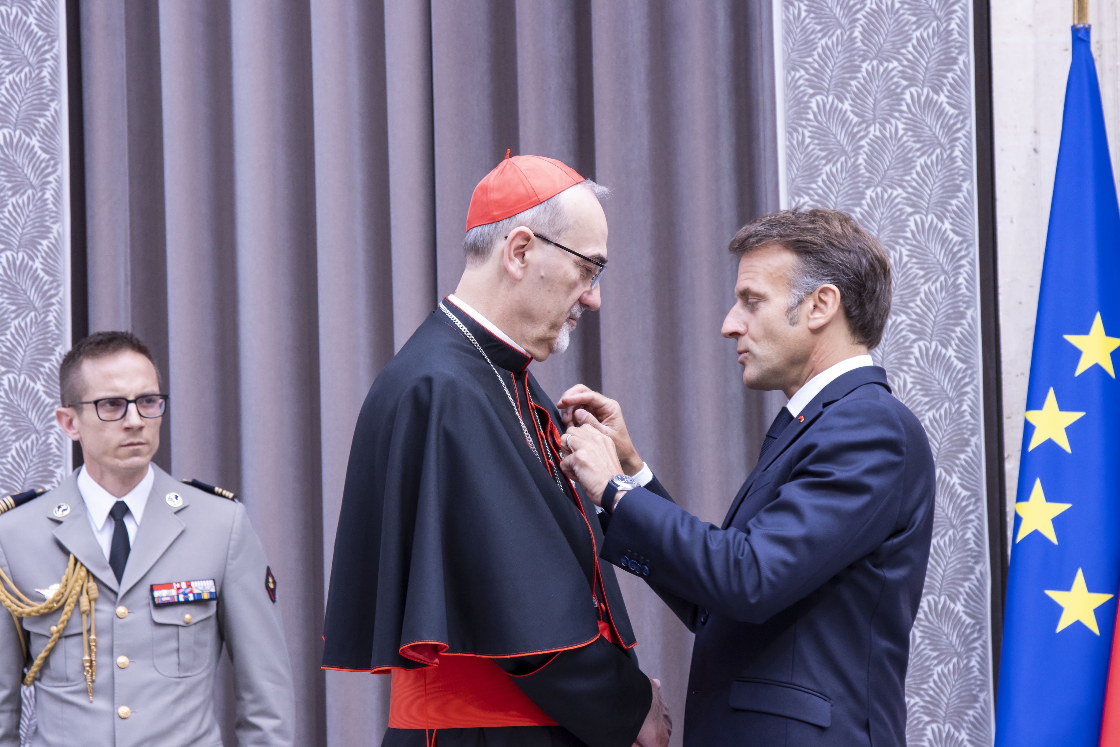 French President Emmanuel Macron, right, awards Cardinal Pierbattista Pizzaballa, the Latin patriarch of Jerusalem, the rank of officer in the Legion of Honor on June 9, 2026, at the Élysée Palace in Paris. | Credit: Sanad Sahelia/ACI MENA