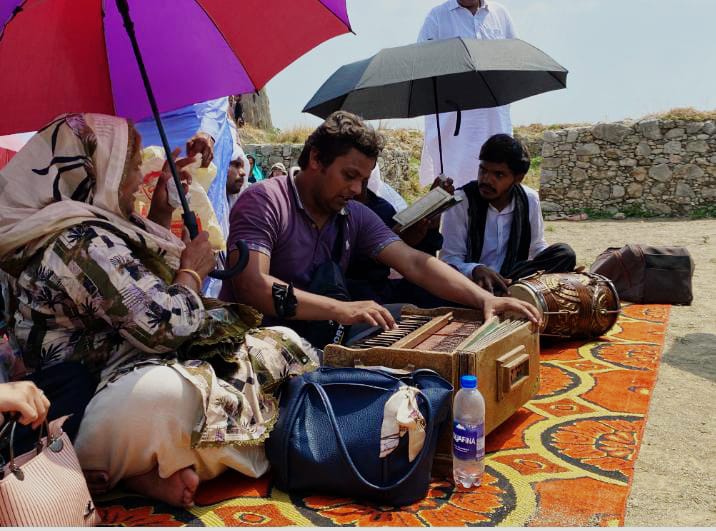 Catholics shelter under umbrellas as Father Yousaf Yaqoob celebrates Mass at the throne of St. Thomas at Sirkap in Taxila, Pakistan, on July 4, 2026. | Credit: Photo courtesy of Sagar Rahat