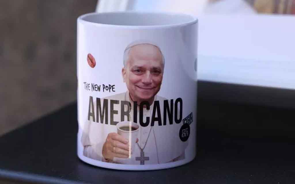 Un retrato del Papa León XIV adorna una taza de café con la palabra "Americano", que hace referencia tanto a la nacionalidad del Papa León XIV como a un tipo de café italiano popular, frente a una caf...