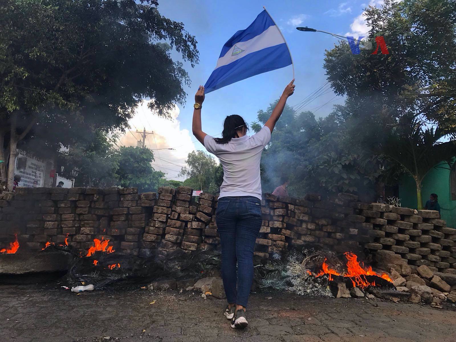 Joven sostiene una bandera nicaraguense cerca de una barricada policial en medio de las protestas del 20 de abril de 2018 en Nicaragua. Crédito: Voice of America / Dominio público.
