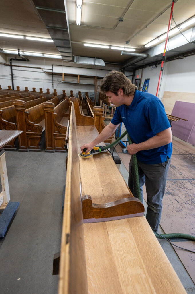 A worker at Fresh Air Finishers in Saint Paul, Minnesota, restores a pew from the Basilica of Saint Mary in an undated photograph. | Credit: Ken Fournelle/Courtesy of the Basilica of Saint Mary