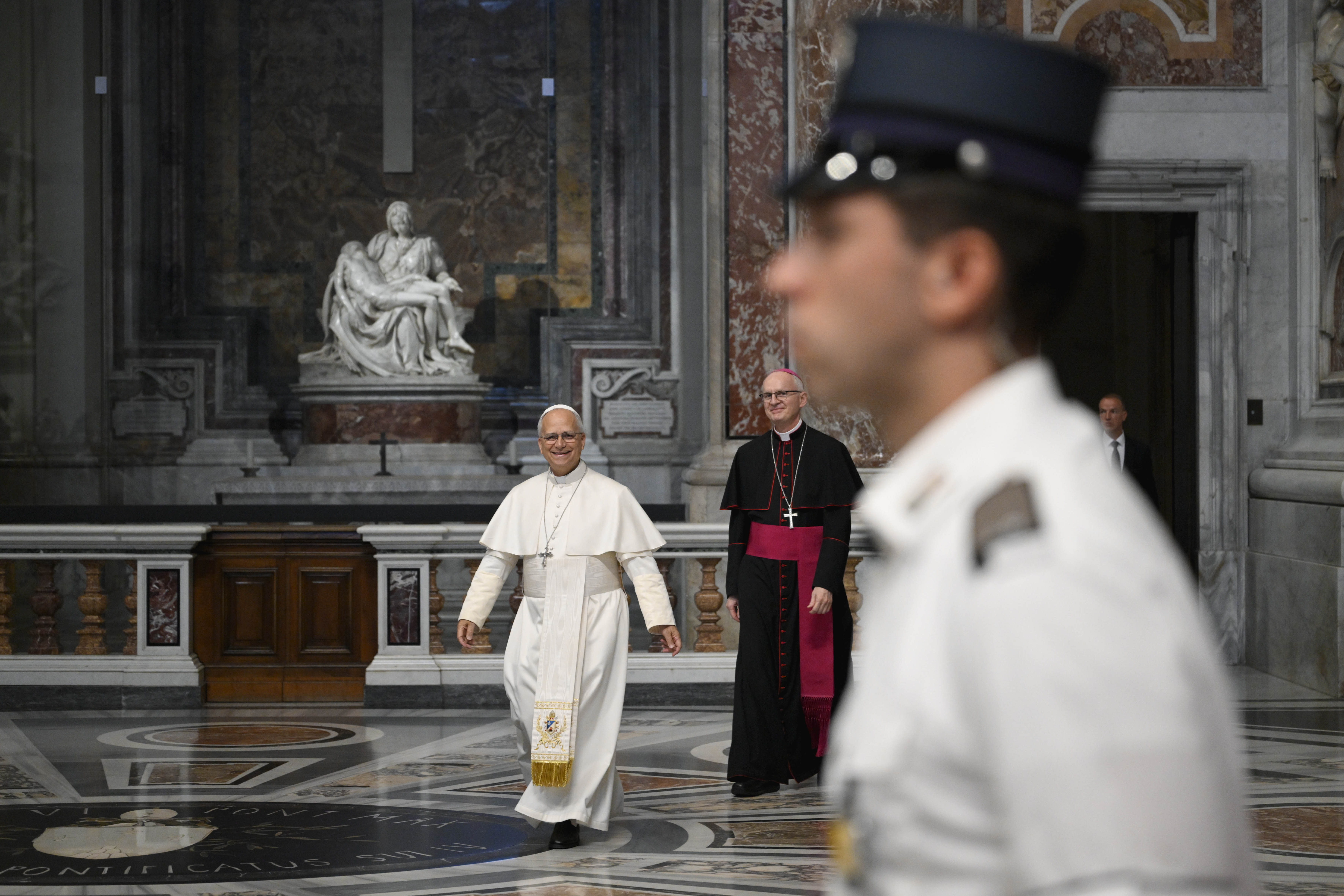 A Vatican gendarme stands guard as Pope Leo XIV walks past Michelangelo's 