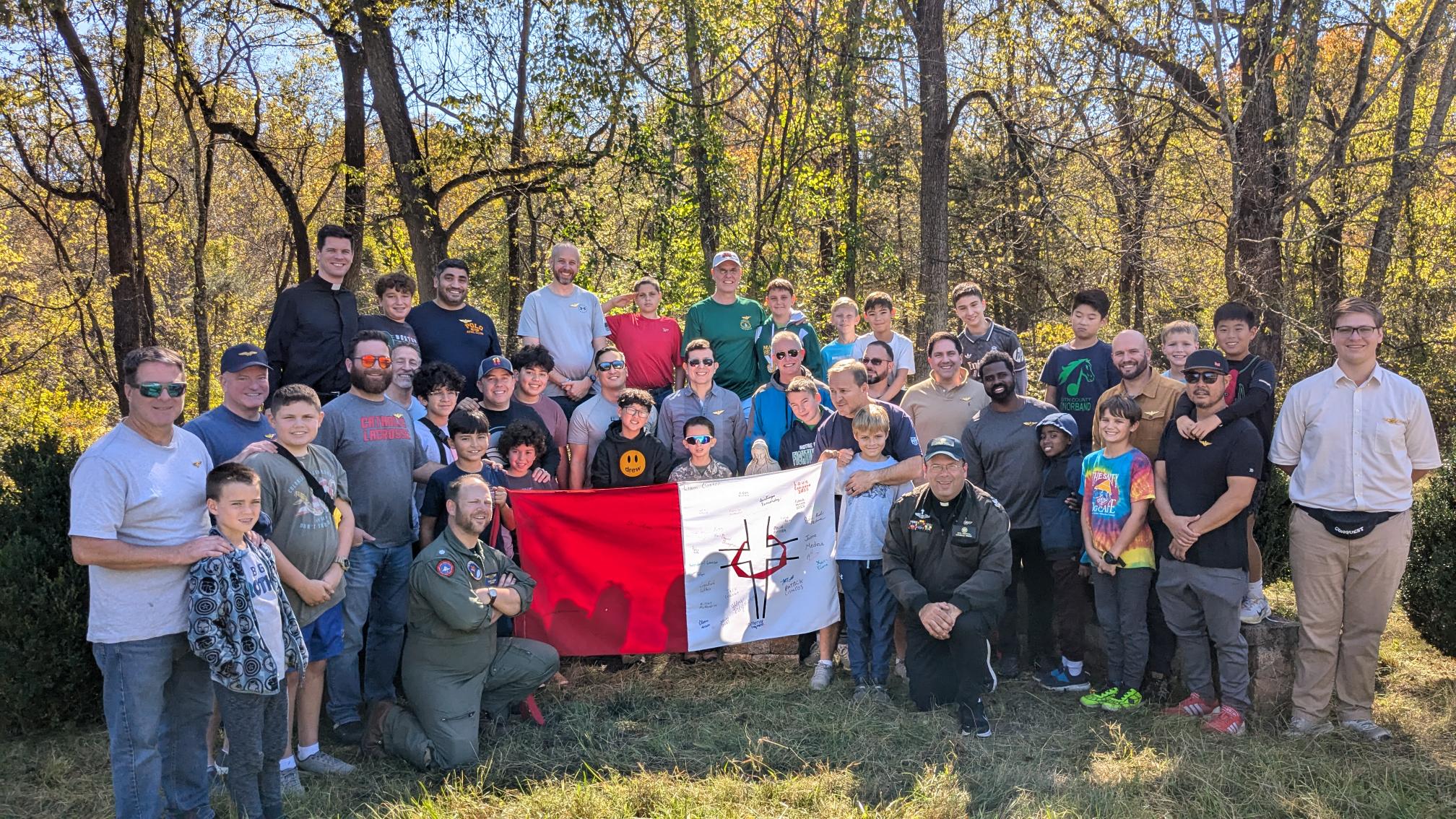Father Vito Crincoli and Top Gun Father and Son weekend participants hold the Encounters, Convictions, and Your Decisions flag at the 2024 Top Gun Father and Son weekend event at Camp Castleton in Virginia. | Credit: Photo courtesy of Father Vito Crincoli