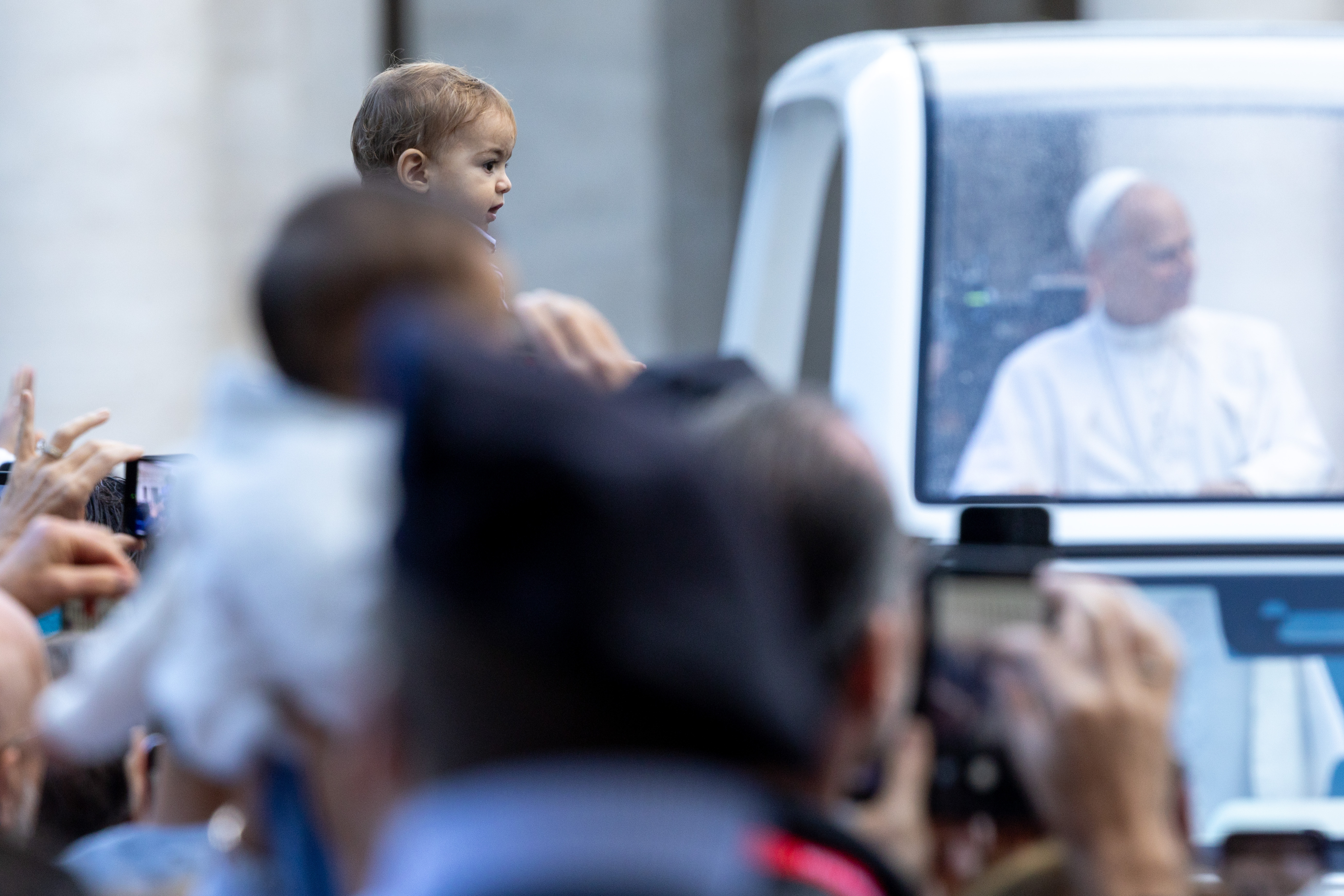 Un niño en brazos espera el paso del Papa. Crédito: Daniel Ibáñez/EWTN