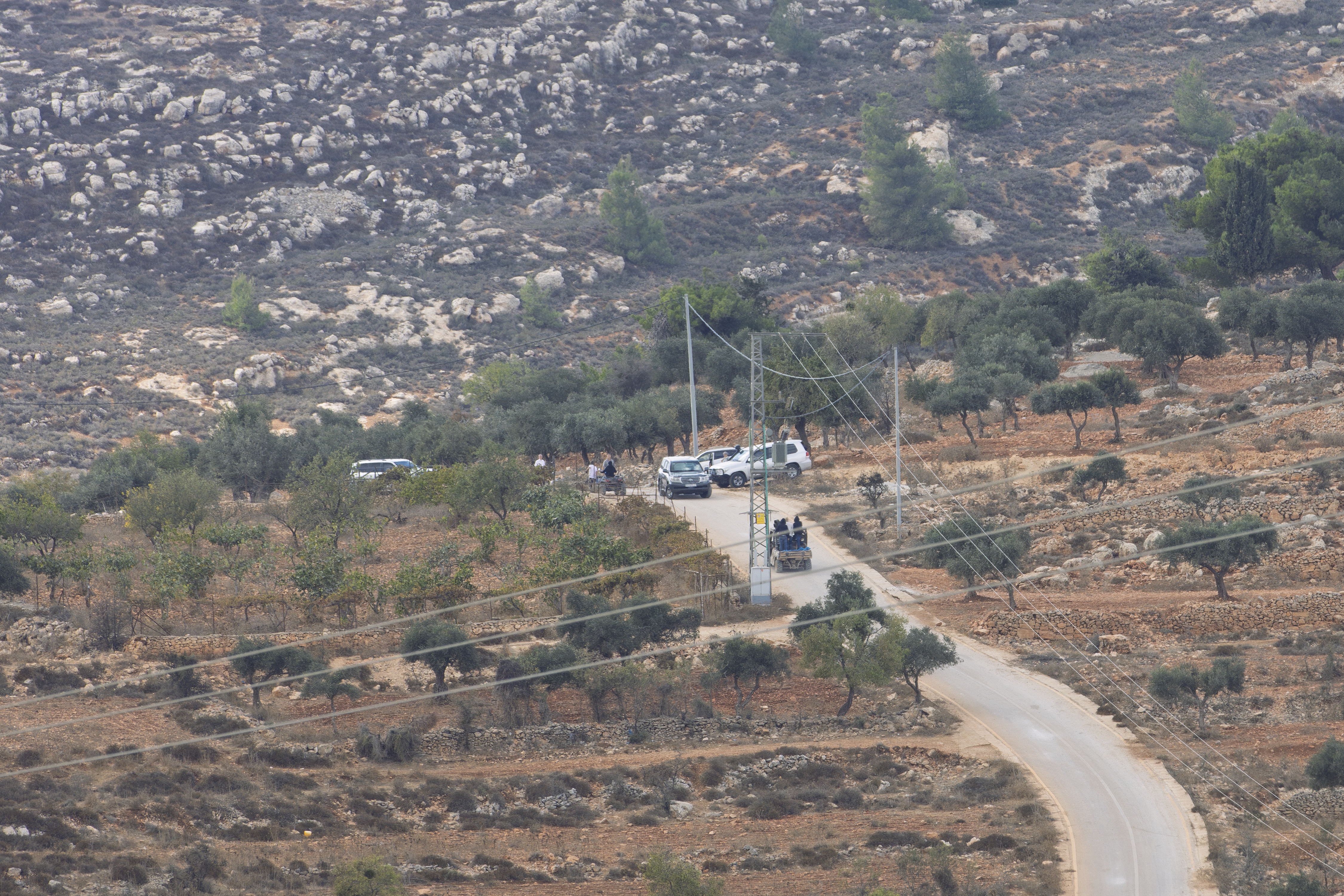 Another view of settlers in off-road buggies pursuing visiting diplomatic delegations and local residents on farmland in Taybeh. | Credit: Sanad Sahelia