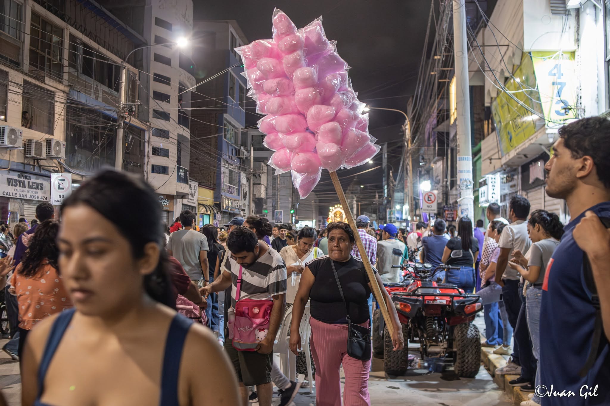 La vida del vendedor ambulante. La marchante de algodones de azúcar rosados abriéndose paso entre la multitud; el retrato perfecto de la cultura popular que envuelve la fiesta. Foto: Juan Gil