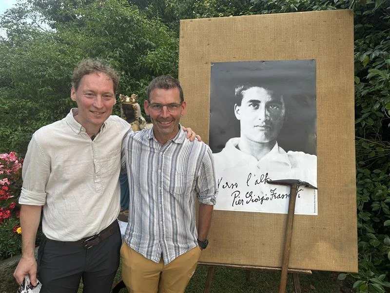 Broers Vincent (links) en Cedric Ebiner poseren voor een foto van Pier Giorgio Frassati nadat ze uit Zwitserland waren gereisd om de vieringen in Pollone, Italië, bij te wonen, donderdag 3 juli 2025. Credit: Courtney Mares/CNA