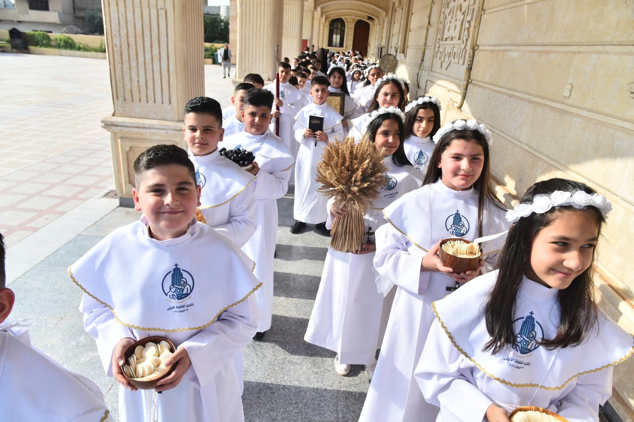 Kinderen lopen de kerk binnen in Qaraqosh, Irak, om hun eerste heilige Communie te vieren. Meer dan 450 jongens en meisjes ontvingen het sacrament tijdens liturgieën die de afgelopen maand in verschillende kerken van de stad werden gehouden. Credits: Syrisch-Katholieke Aartsbisdom van Mosul, Irak