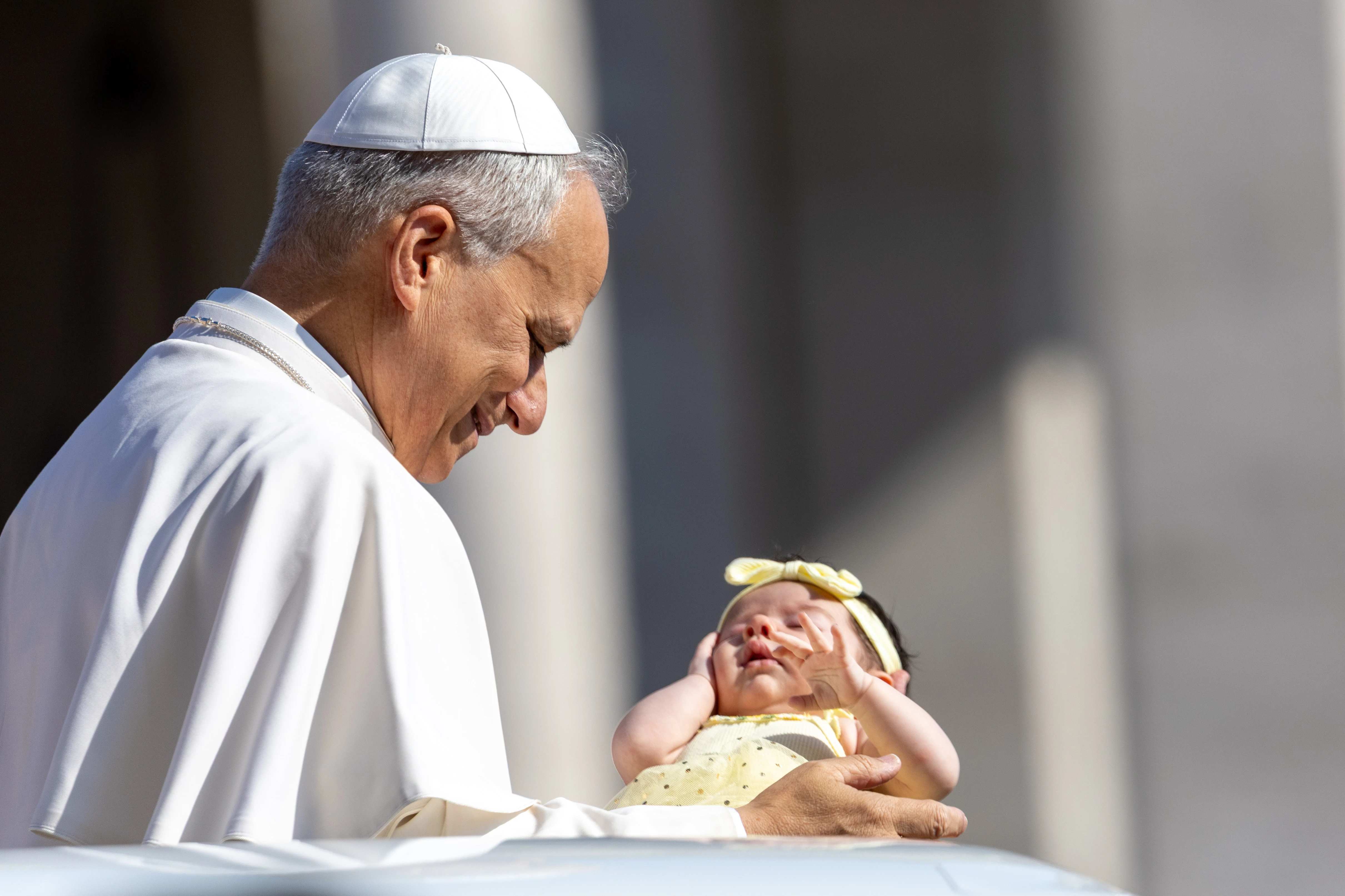 Paus Leo XIV zegent een baby tijdens zijn woensdagse algemene audiëntie op 6 augustus 2025 op het Sint-Pietersplein in Vaticaanstad. Credit: Daniel Ibañez/CNA