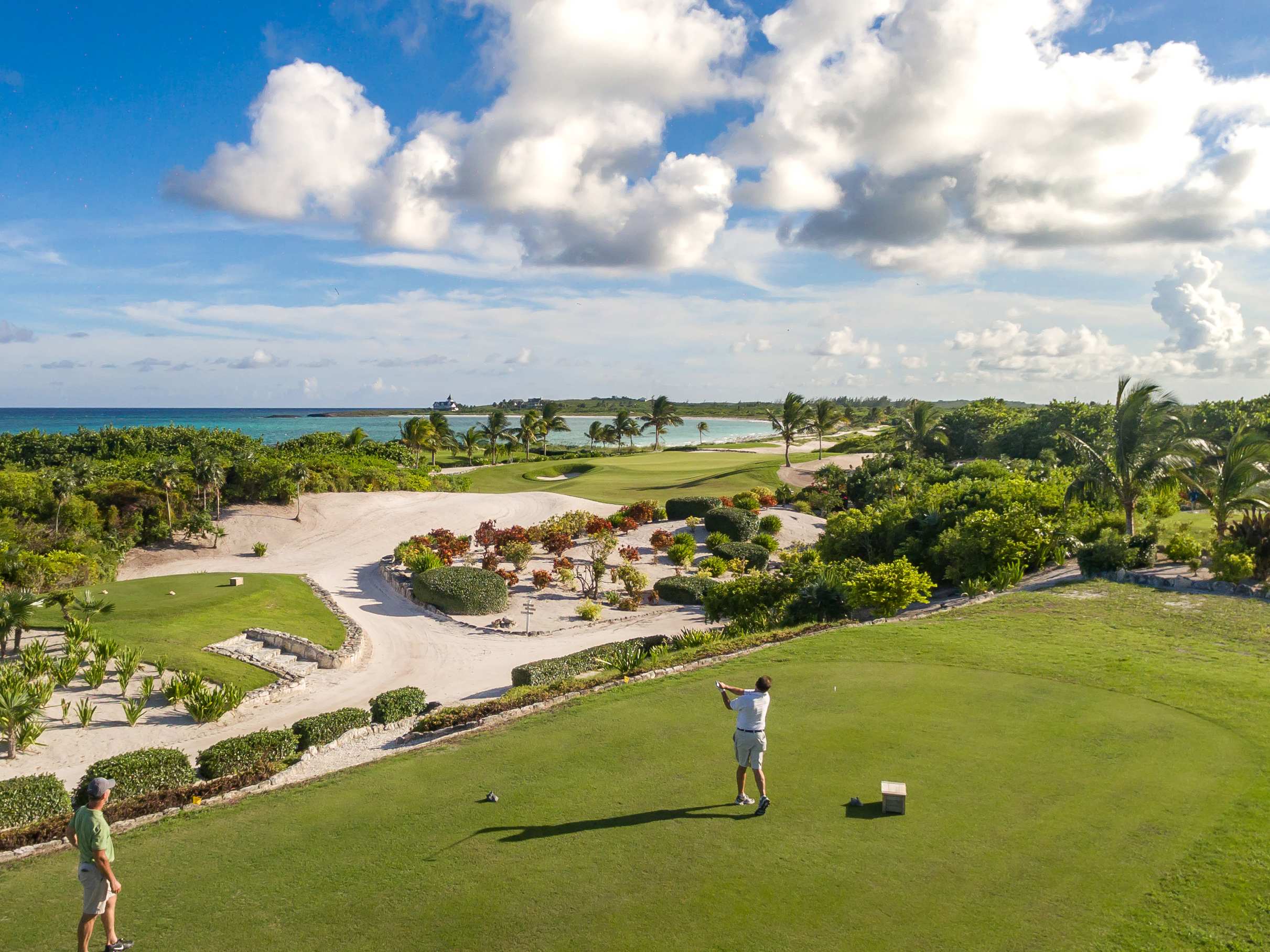 Golfers enjoying a round of golf at The Abaco Club with ocean views and lush greenery in the background.