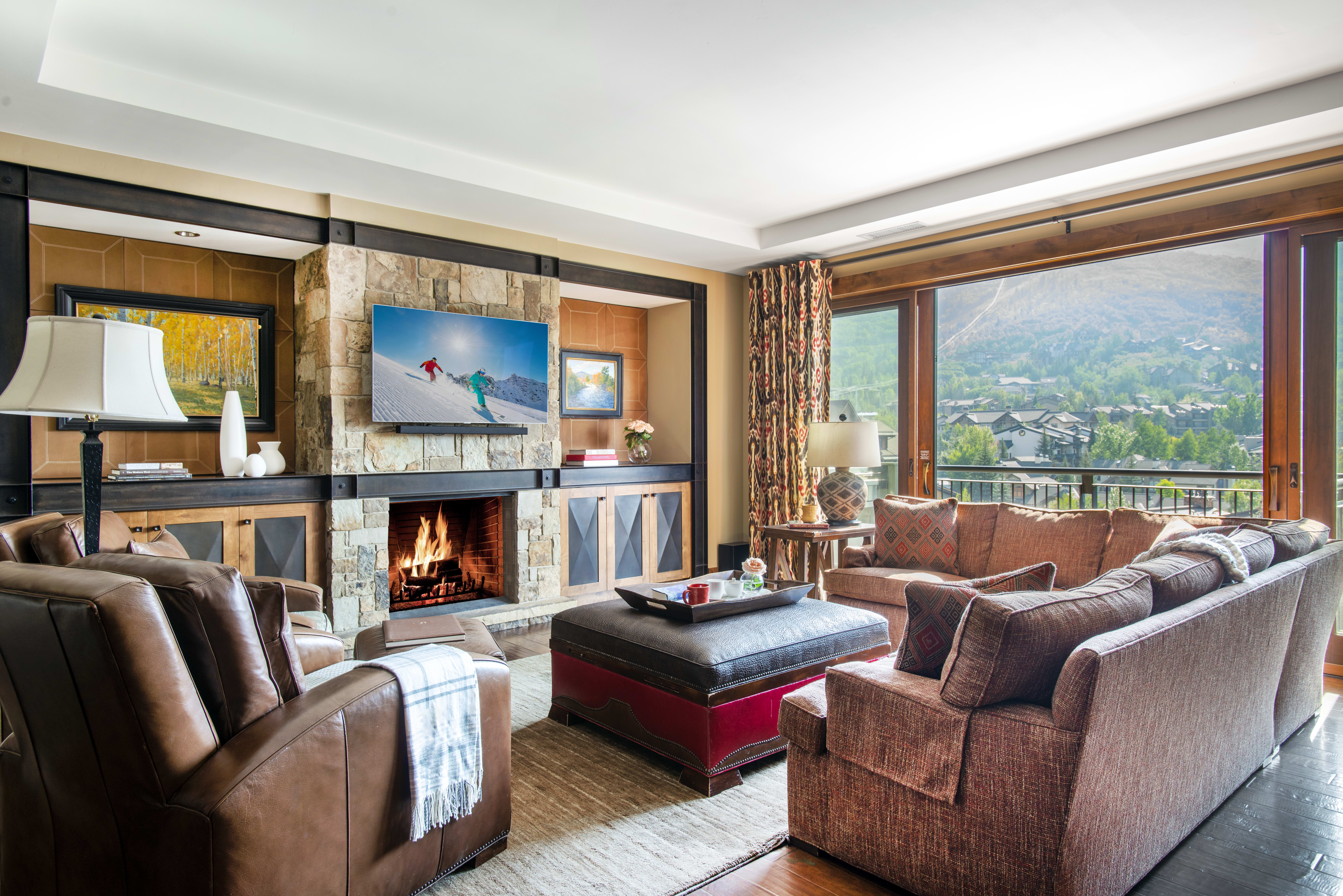 Living room in an Exclusive Resorts property at One Steamboat Place with stone fireplace and mountain views.