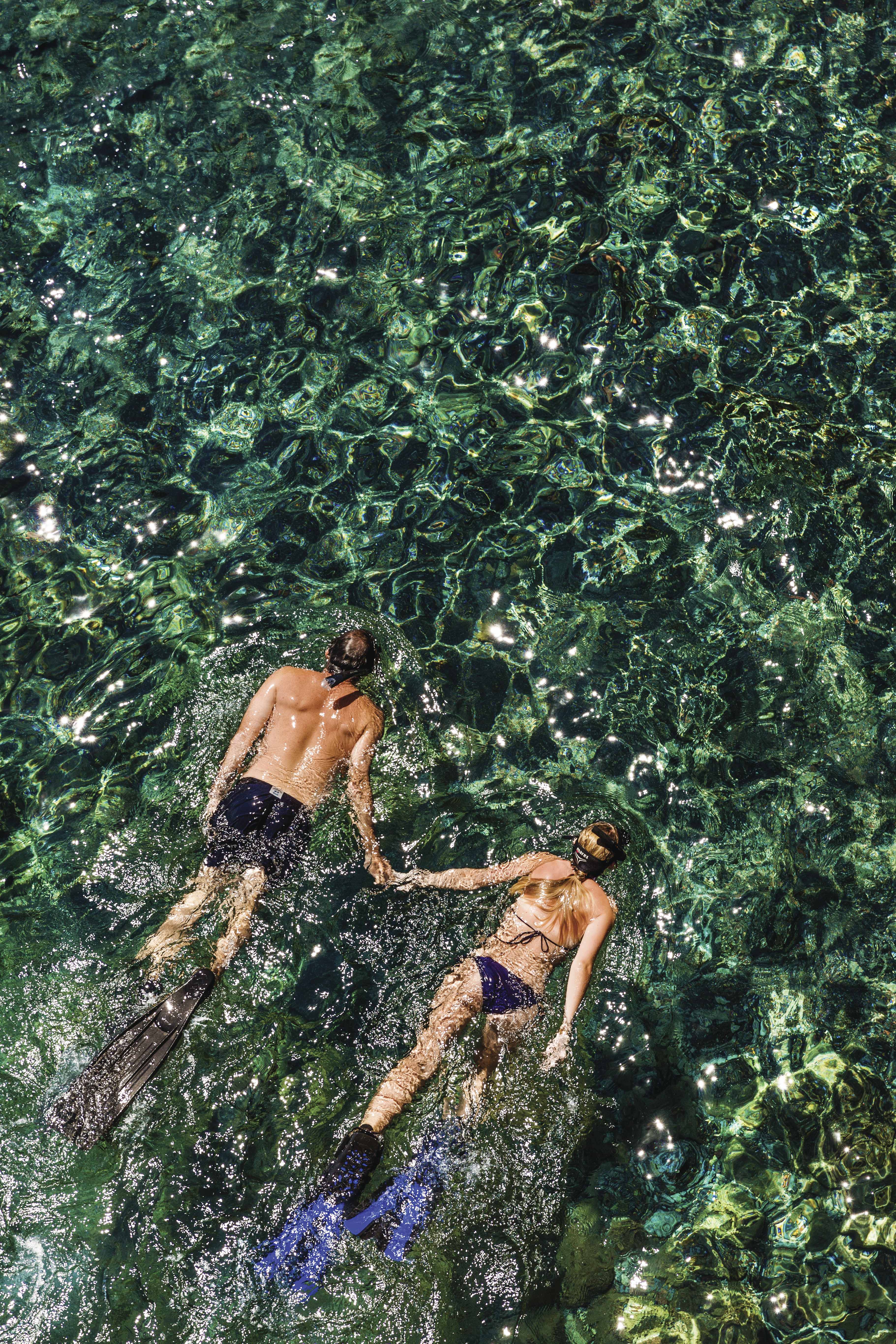 A couple snorkeling together in clear, sparkling waters.