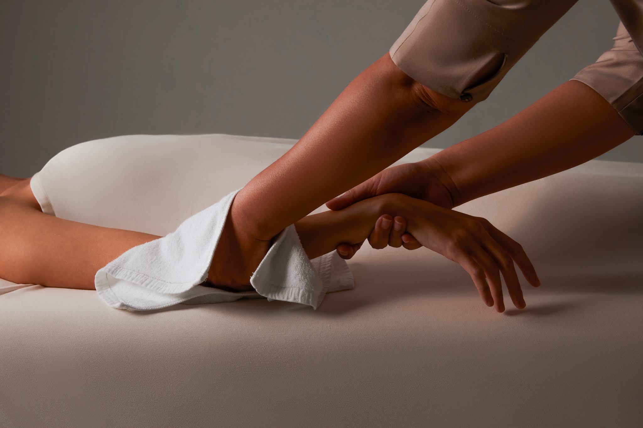 Close-up of a massage therapist performing a relaxing arm massage on a person lying on a massage table.