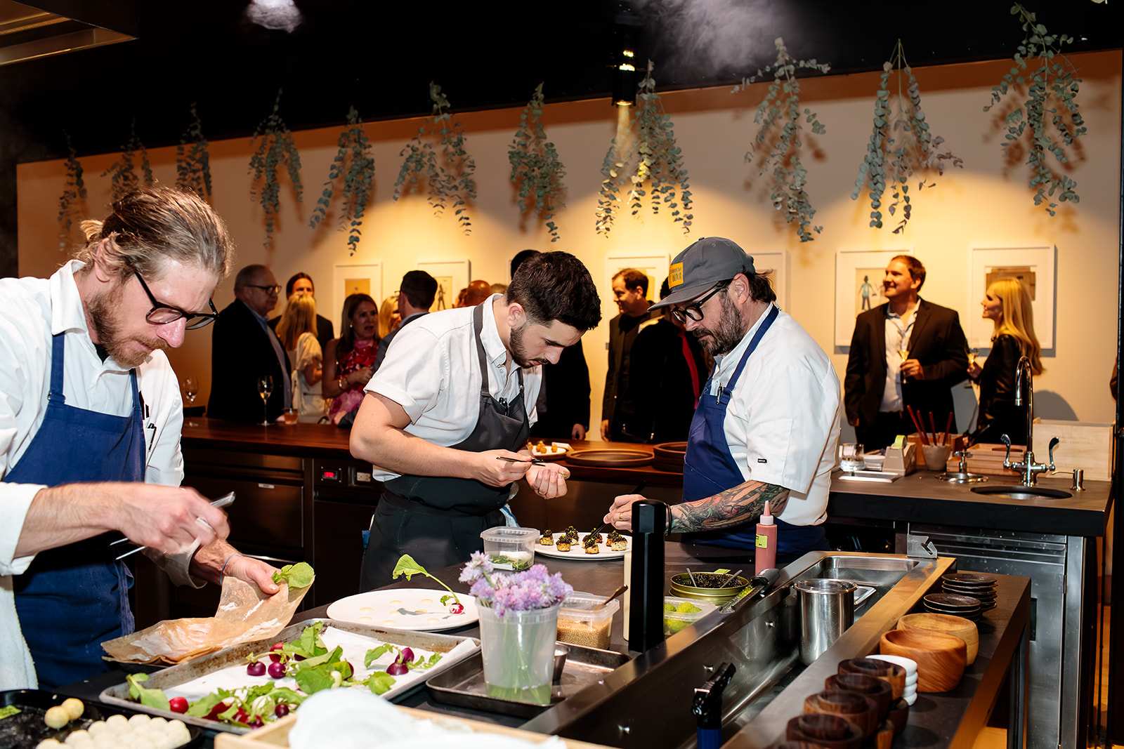 Chefs preparing dishes in an open kitchen while guests observe during a culinary event with Exclusive Resorts.