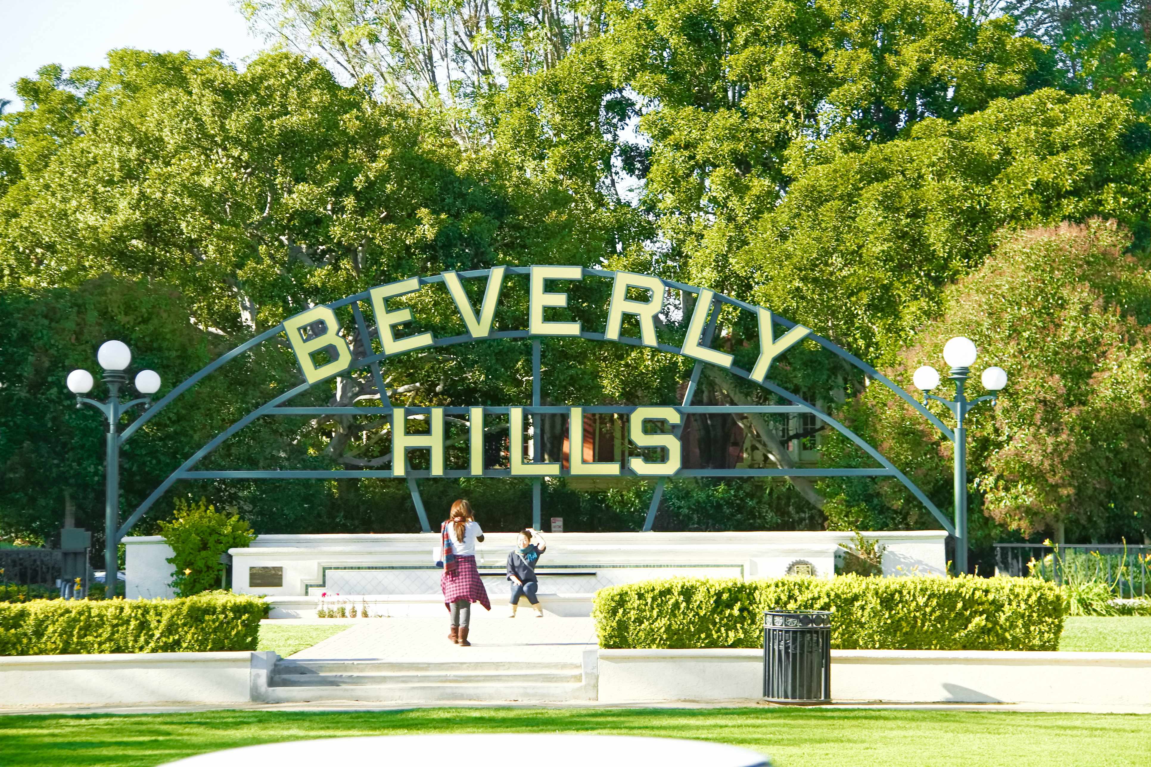 The iconic Beverly Hills sign in a park setting with visitors in the foreground.