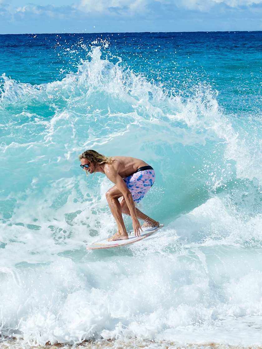 Surfer riding a wave in crystal blue ocean waters.