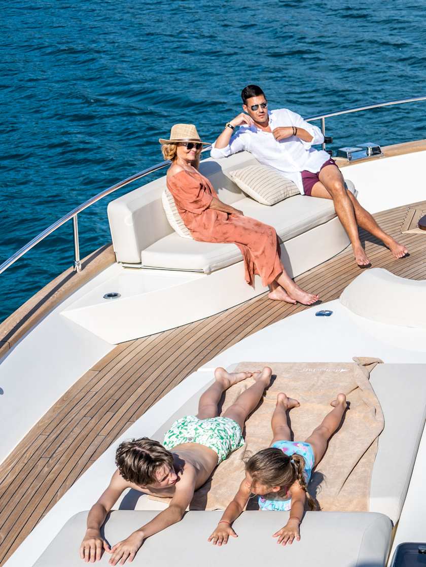 Exclusive Resorts' Members relaxing on the deck of a yacht, with two children sunbathing and adults seated, enjoying the ocean view.