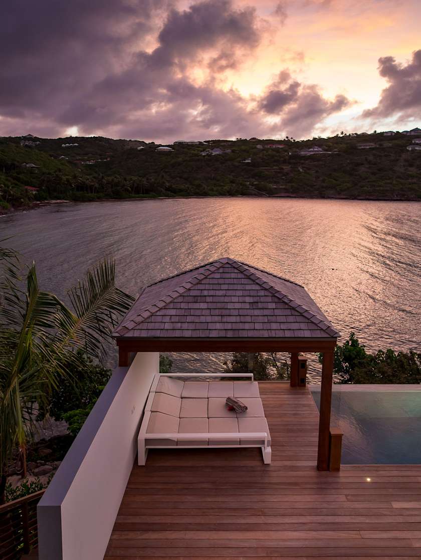 Sunset view from Exclusive Resorts' villa in St. Barts, featuring a private deck with a gazebo overlooking the calm waters.