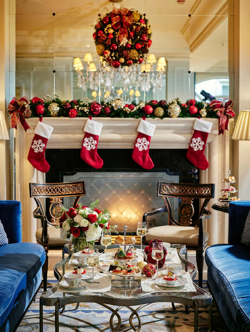 Cozy Christmas-themed afternoon tea setup by a decorated fireplace at The Peninsula Beverly Hills.