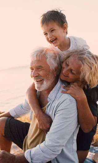 Couple de grands-parents souriants avec leur petit fils à la plage