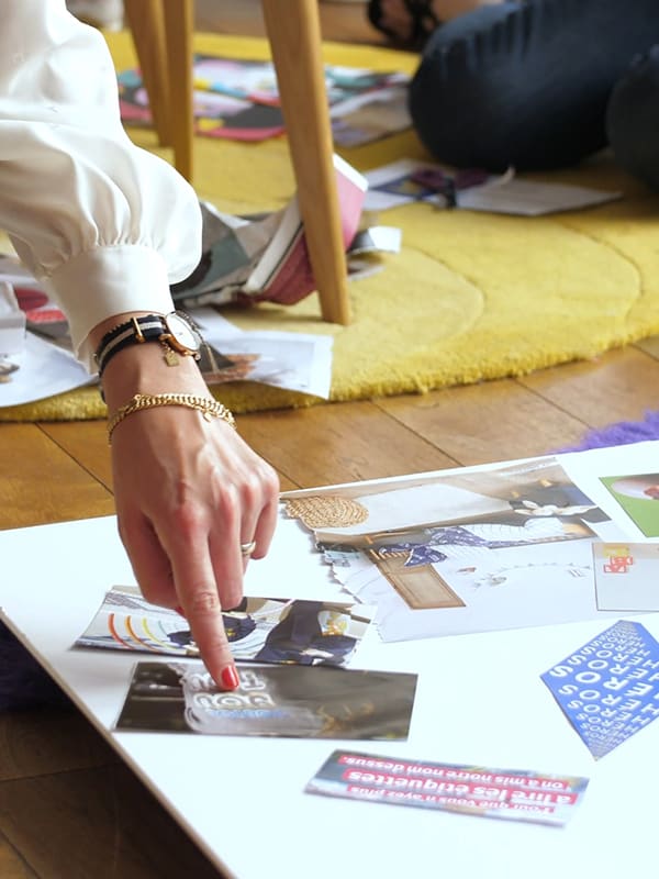 A hand shows one of the images pasted on a white cardboard placed on the ground