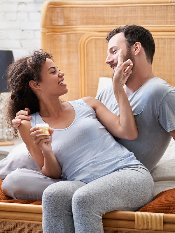  A couple sitting on a bed and smiling at each other