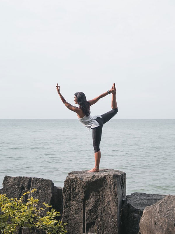 Mujer haciendo yoga en una roca