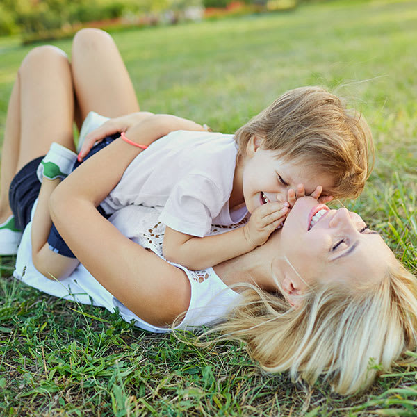 Une maman fait un calin à sa fille allongées dans l'herbe