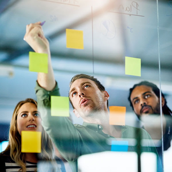 Three people in front of a blackboard with post-it notes